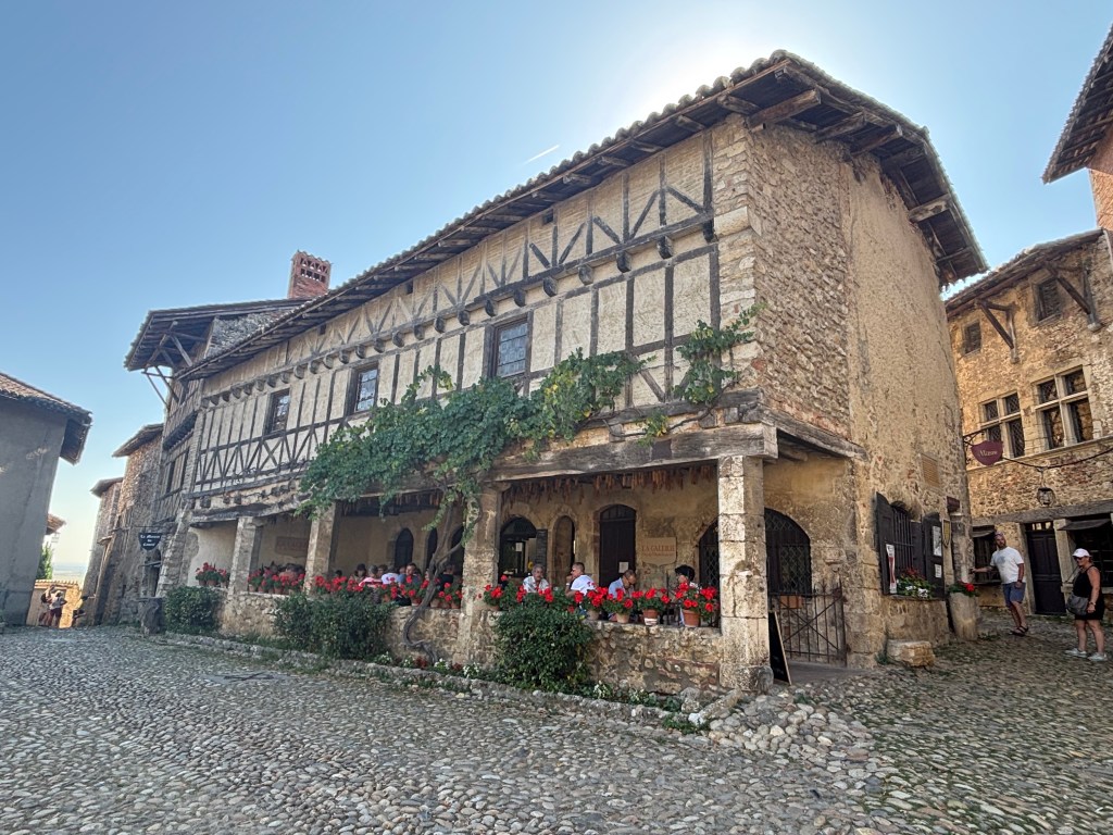Casa medievale a graticcio con portico fiorito nella piazza principale di Pérouges